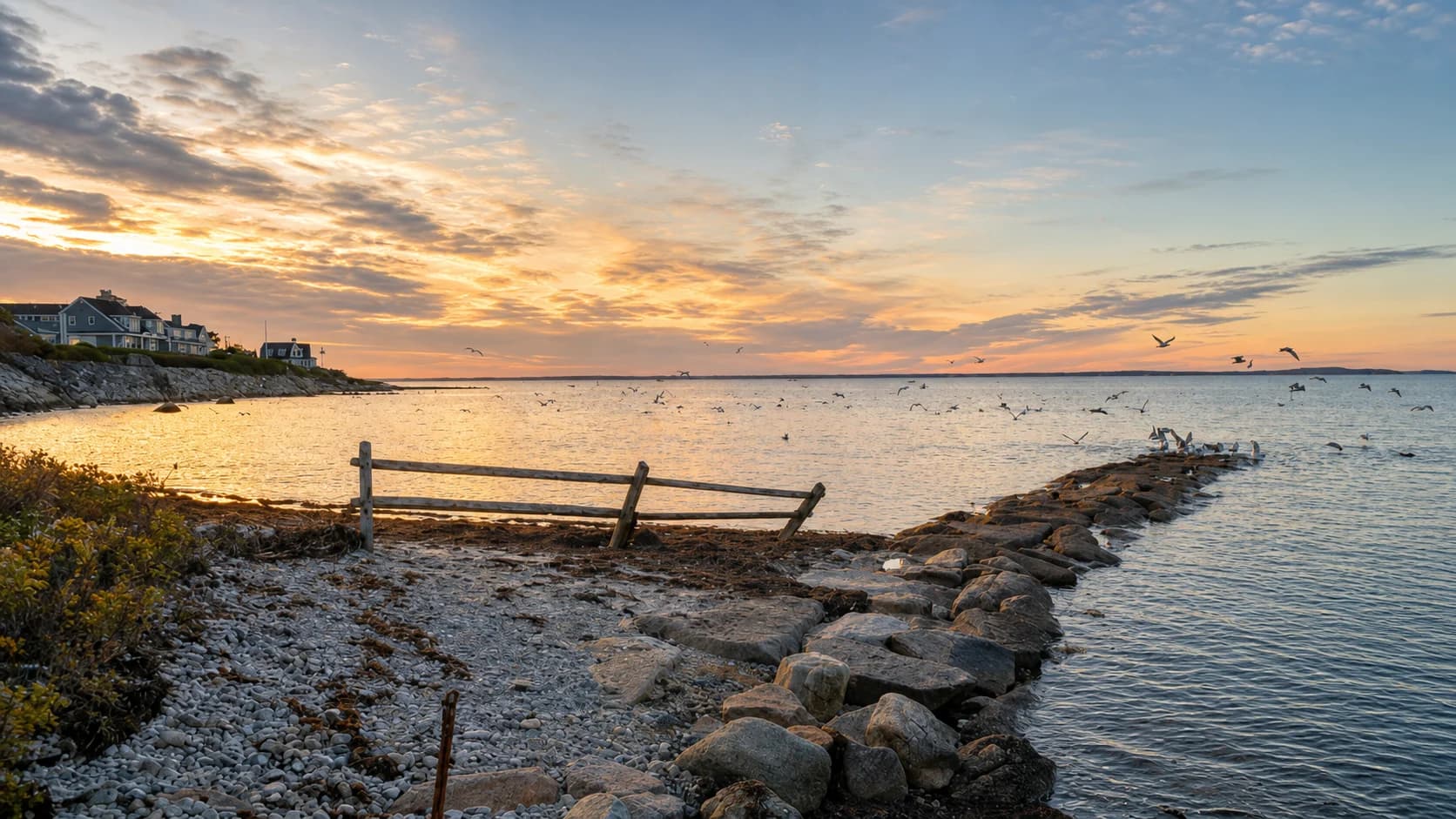 A weathered fence and stone jetty overlooking Nyes Neck at sunset